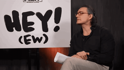Man Sitting In Front Of Hey Ew Sign GIF