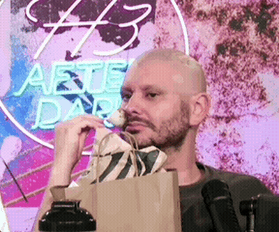 Man Sitting In Front Of Neon Sign Saying #3 GIF