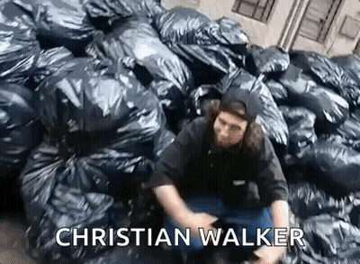 Man Sitting In Front Of Pile Of Trash Bags GIF