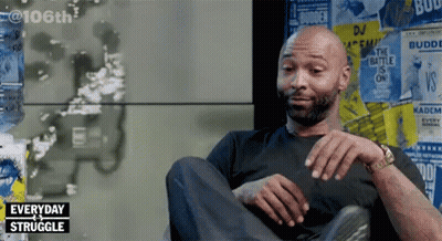 Man Sitting In Front Of Posters Saying Everyday Struggle GIF