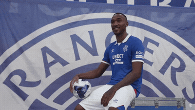 Man Sitting In Front Of Rangers Logo Holding Soccer Ball GIF