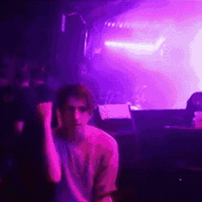 Man Sitting In Front Of Stage With Purple Lights GIF