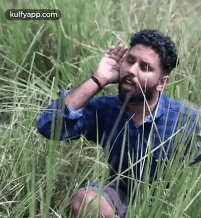 Man Sitting In Grass Covering Ears GIF