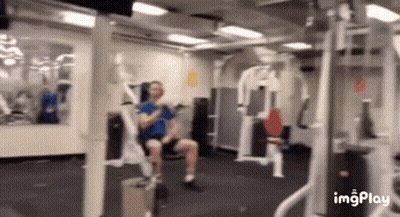 Man Sitting in Gym Using Machine