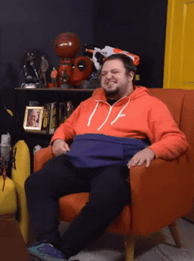 Man Sitting In Orange Chair With Picture Behind GIF