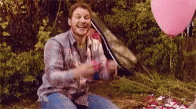 Man Sitting In Woods With Pink Balloons And Tent GIF
