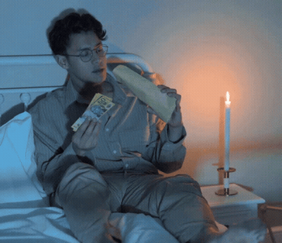 Man Sitting On Bed Holding Paper Saying 50 GIF