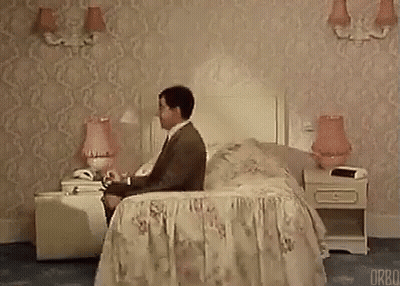 Man Sitting On Bed In Hotel Room Talking On Cell Phone GIF