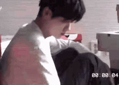 Man Sitting On Bed With Clock Saying 00:00 GIF