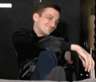 Man Sitting On Bed With Crossed Legs Smiling GIF