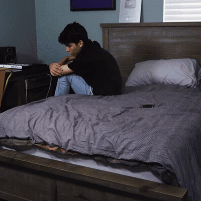 Man Sitting On Bed With Silver Plaque GIF