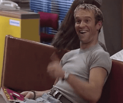 Man Sitting On Bench In Restaurant Laughing Holding Magazine GIF