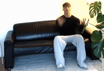 Man Sitting On Black Leather Couch Hands Up GIF