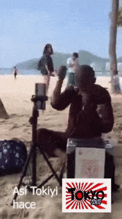 Man Sitting On Box On Beach With Tokyo Logo GIF