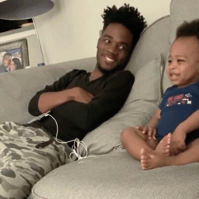 Man Sitting On Couch Holding Baby With Big Chill Shirt GIF