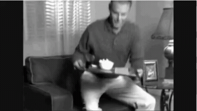 Man Sitting On Couch Holding Food Tray GIF