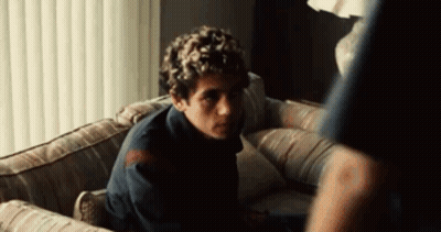 Man Sitting On Couch In Dark Room Looking At Something GIF