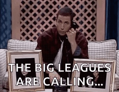 Man Sitting On Couch Talking On Phone Holding Two Framed Pictures GIF
