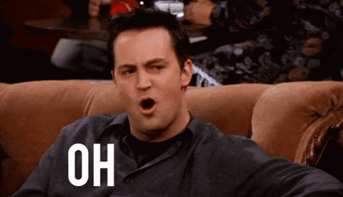 Man Sitting On Couch With Mouth Open And Word Oh On Chest GIF