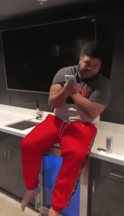 Man Sitting On Counter Looking At Phone GIF