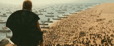 Man Sitting On Hill Overlooking Boats And Soldiers GIF