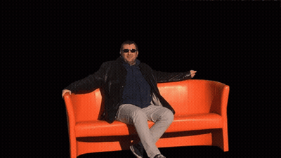 Man Sitting On Orange Couch In Front Of Explosion GIF