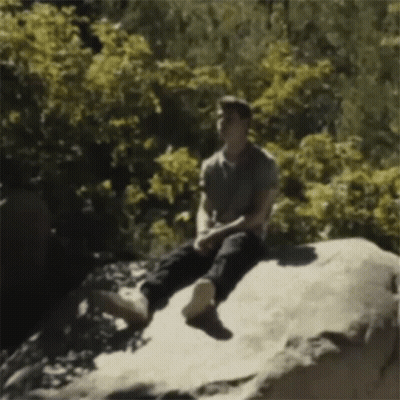 Man Sitting On Rock In Woods GIF