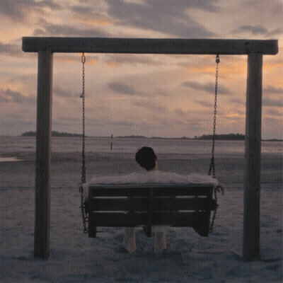 Man Sitting On Swing On Beach GIF