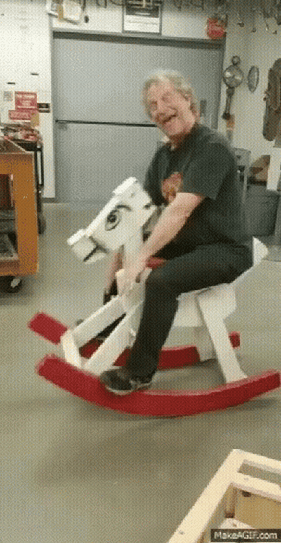 Man Sitting On Wooden Rocking Horse Smiling GIF