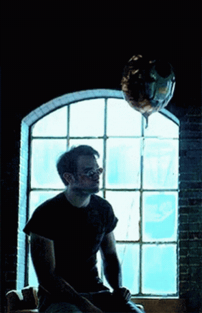 Man Sitting Under Balloon By Window GIF