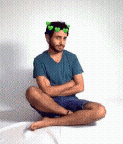 Man Sitting With Arms Crossed And Green Hearts Crown GIF
