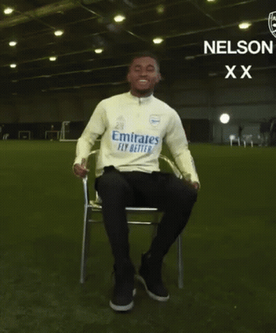 Man Sitting With Arms Outstretched In Emirates Fly Better Shirt GIF