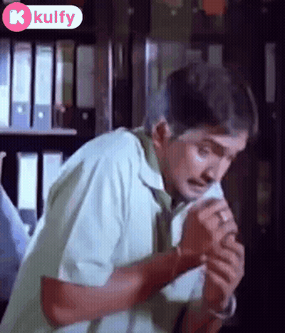 Man Sitting With Folded Hands By Bookshelf GIF