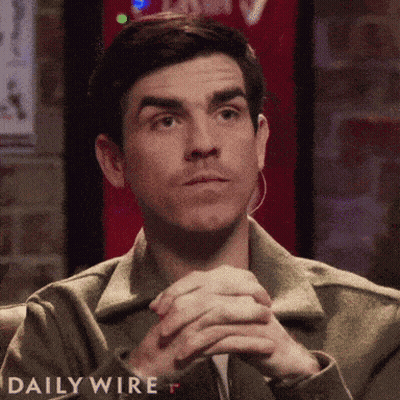Man Sitting With Hands Folded In Front Of Daily Wire Sign GIF