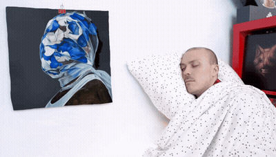 Man Sleeping Before Painting Of Man's Head GIF