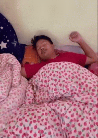 Man Sleeping On Bed With Pink And Cherry Print Blanket GIF