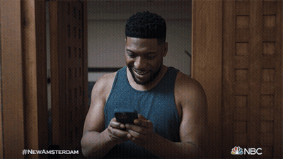 Man Smiling At Cell Phone With NBC Logo GIF