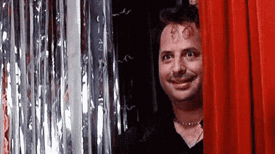 Man Smiling Behind Red Curtain GIF