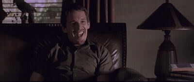 Man Smiling In Chair In Dark Room GIF