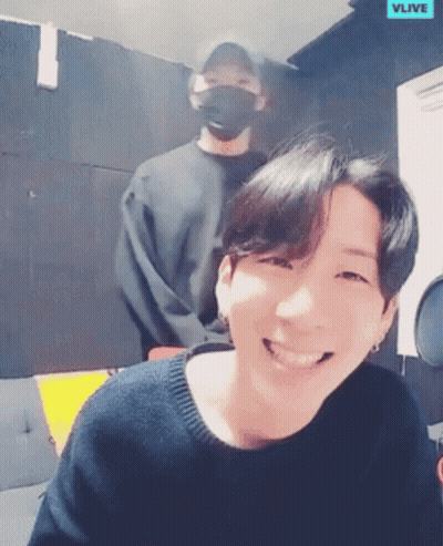 Man Smiling In Front Of Another Man Wearing Mask GIF