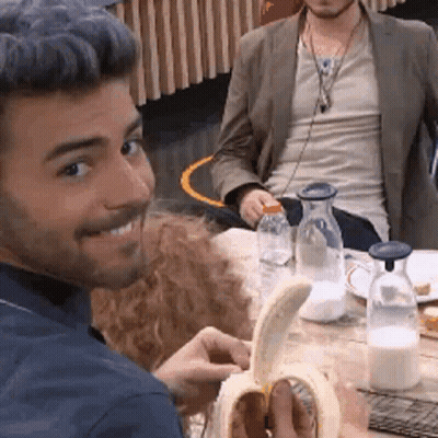Man Smiling While Peeling Banana At Table GIF