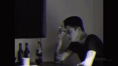 Man Smoking Cigarette At Table With Alcohol GIF
