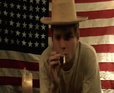 Man Smoking Cigarette In Front Of American Flag GIF