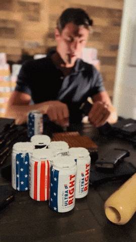 Man Smoking Cigarette in Front of Six Ultra Light Beer Cans