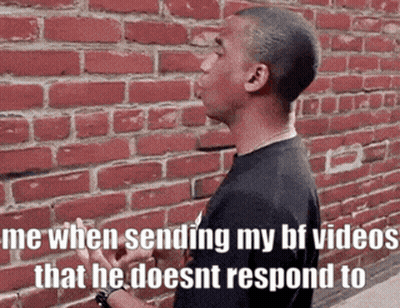 Man Smoking Cigarette Talking By Brick Wall GIF