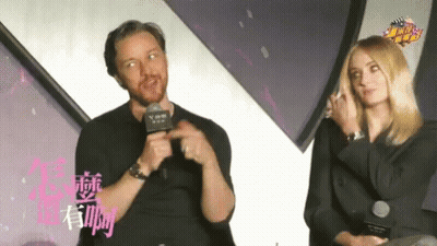 Man Speaking Into Microphone Beside Woman With Chinese Writing GIF