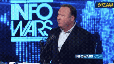 Man Speaking Into Microphone In Front Of Info Wars Screen GIF