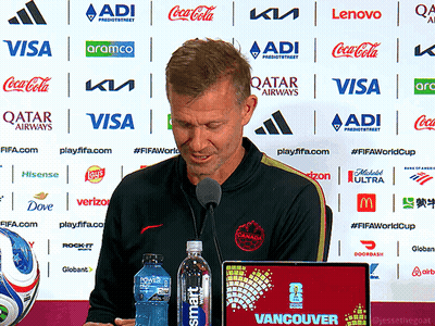 Man Speaking Into Microphone In Front Of Qatar Airways Ads GIF