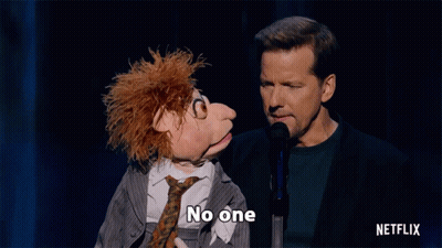 Man Speaking Into Microphone Next To Puppet Saying Cares GIF