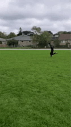 Man Sprinting Across Grassy Field GIF